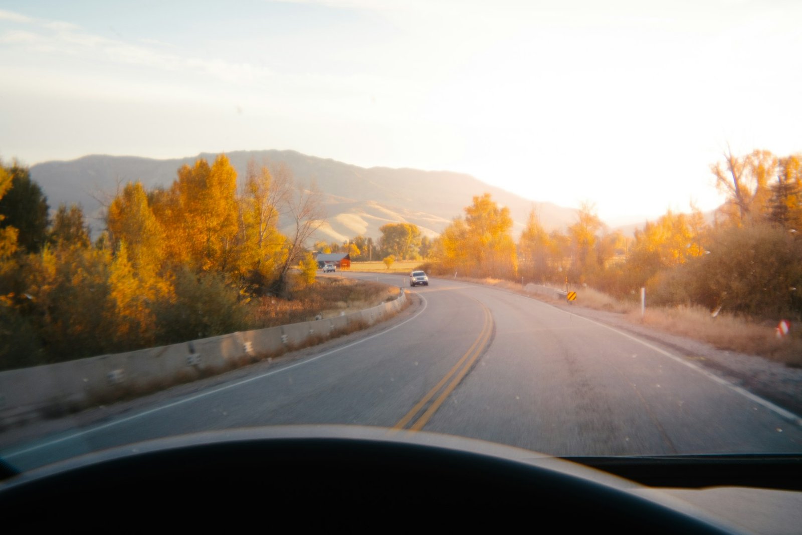 A winding mountain highway surrounded by golden fall foliage near a river in Idaho.